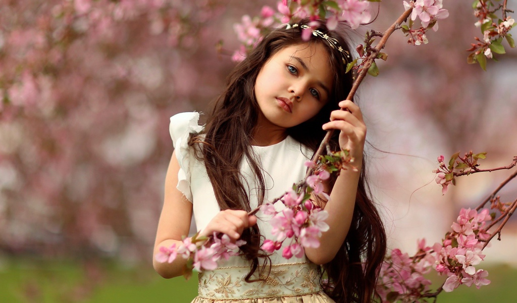 Маленькая девочка у цветущей розовыми цветами ветки