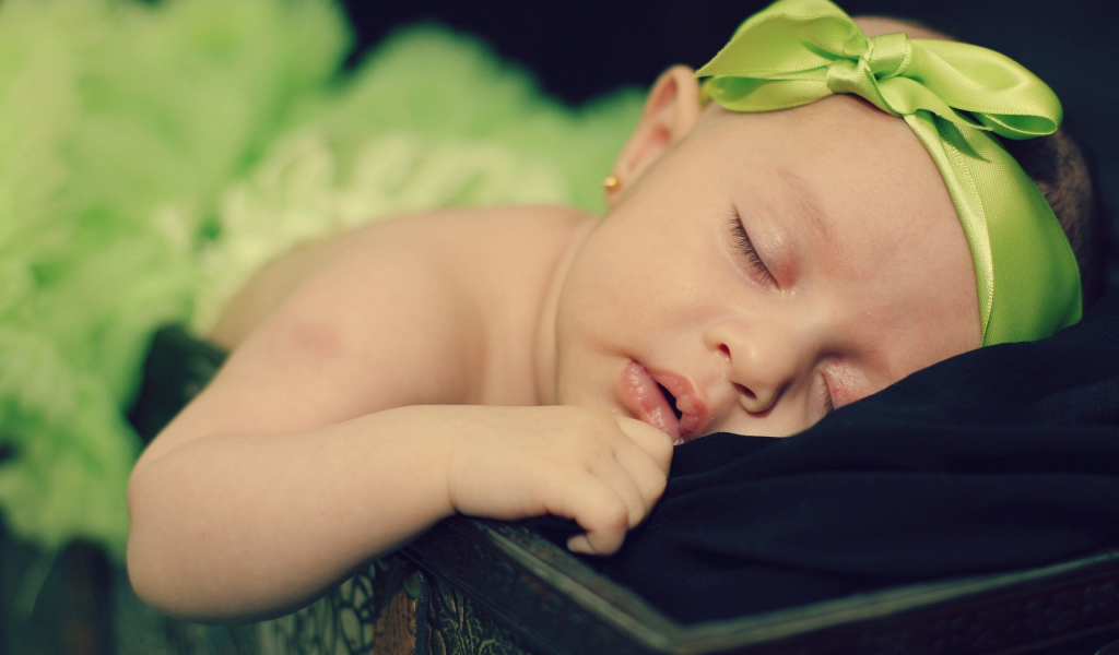 Маленькая спящая девочка с ленточкой на голове