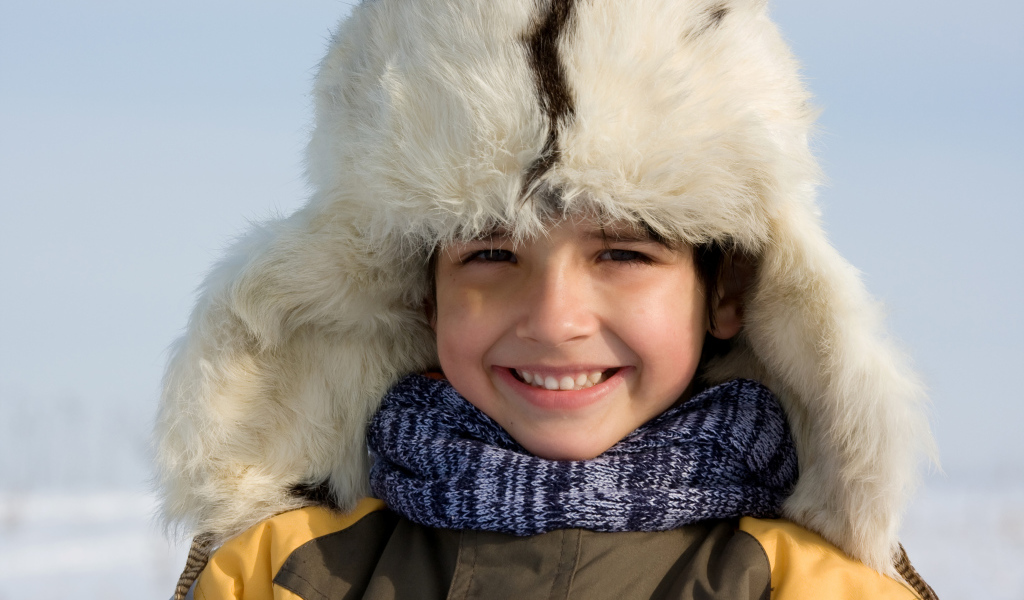 Маленький улыбающийся мальчик в теплой шапке зимой