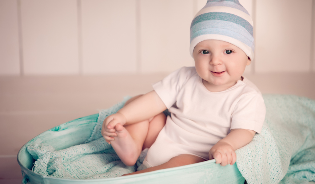 Маленький улыбающийся ребенок сидит в железном тазике