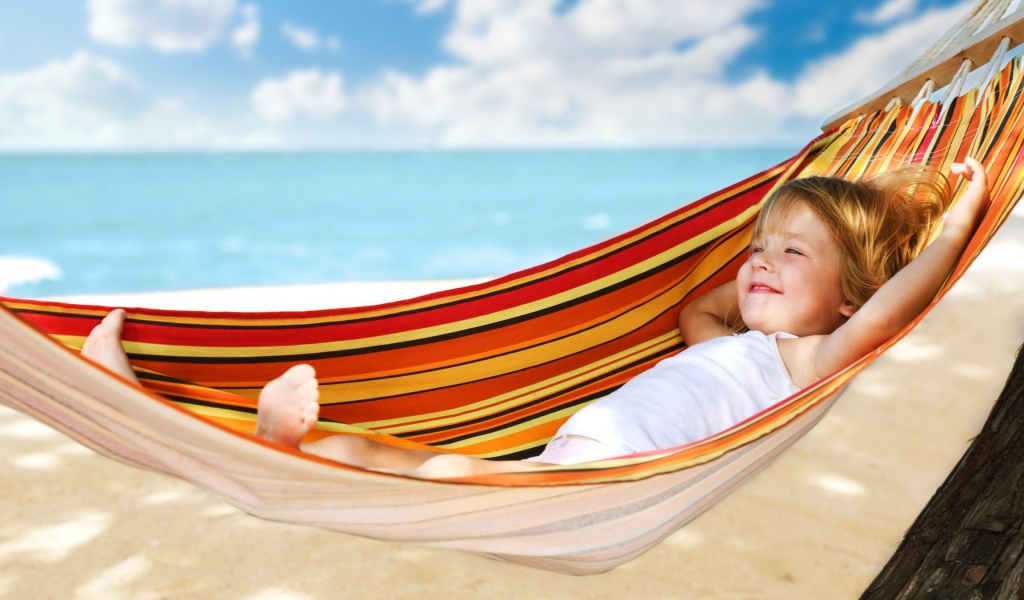 Маленькая улыбающаяся девочка в гамаке на пляже