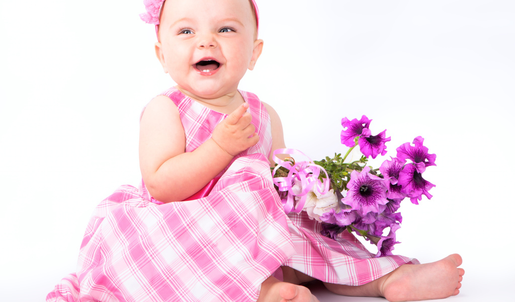 Маленькая улыбающаяся девочка с букетом петунии на белом фоне
