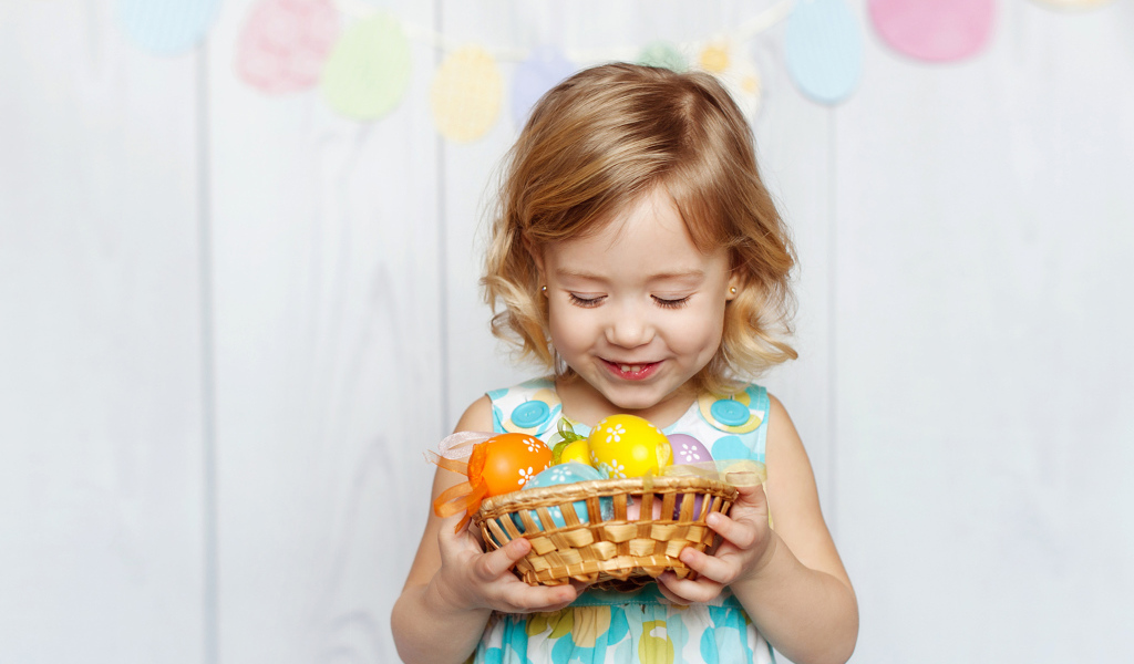 Маленькая улыбающаяся девочка с пасхальными яйцами в руках