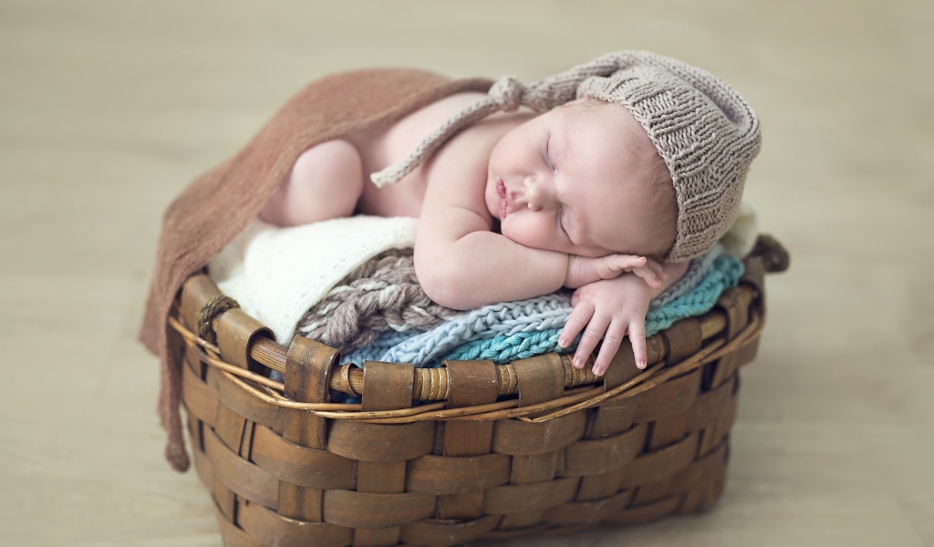 Спящий грудной ребенок в шапке в корзине 