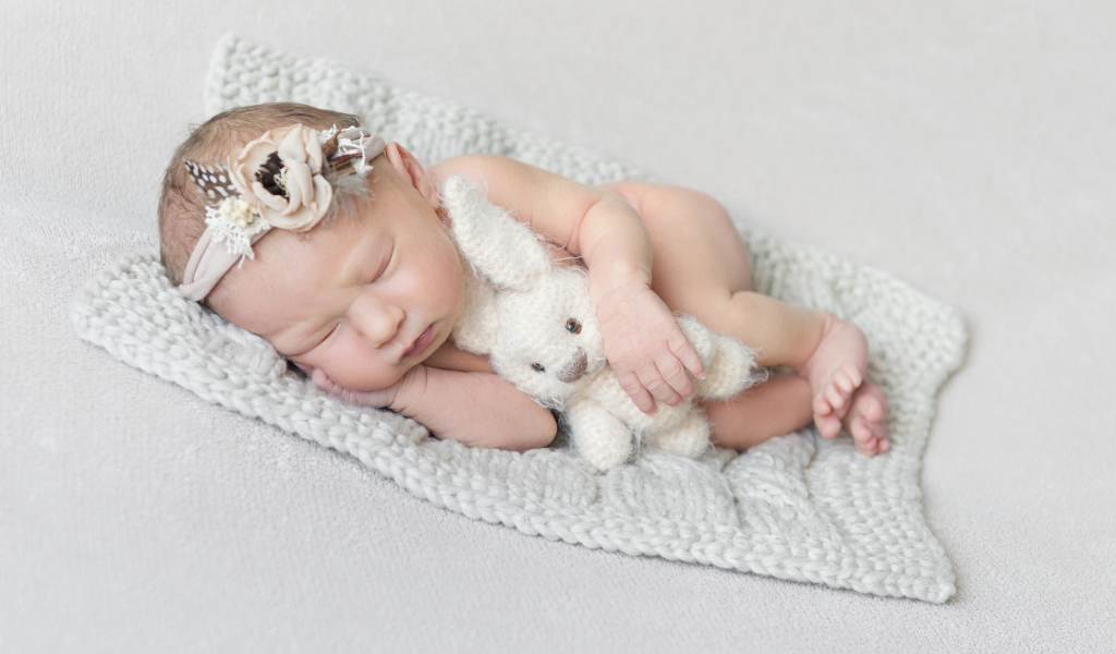 Спящий грудной ребенок с вязаной игрушкой