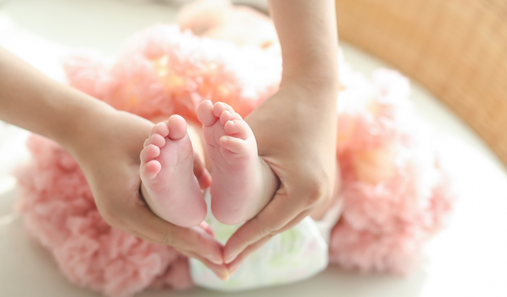 Маленькие ножки новорожденного в ладонях у мамы 