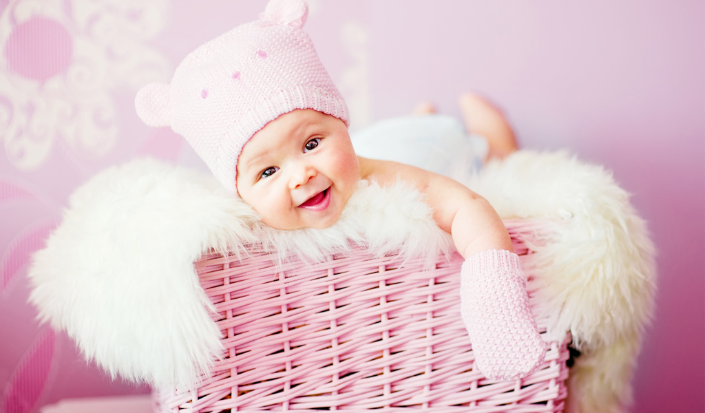 Улыбающийся грудной ребенок лежит в розовой корзине