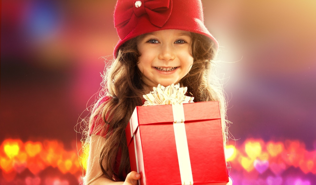 Улыбающаяся голубоглазая девочка с большим подарком в руках