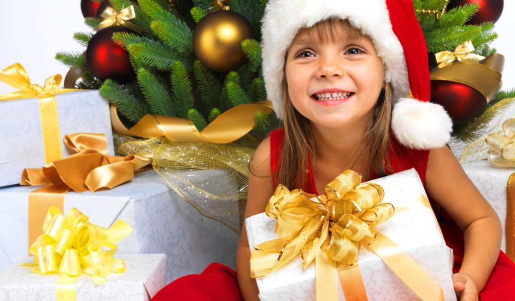 Улыбающаяся девочка в новогоднем костюме с подарками под елкой