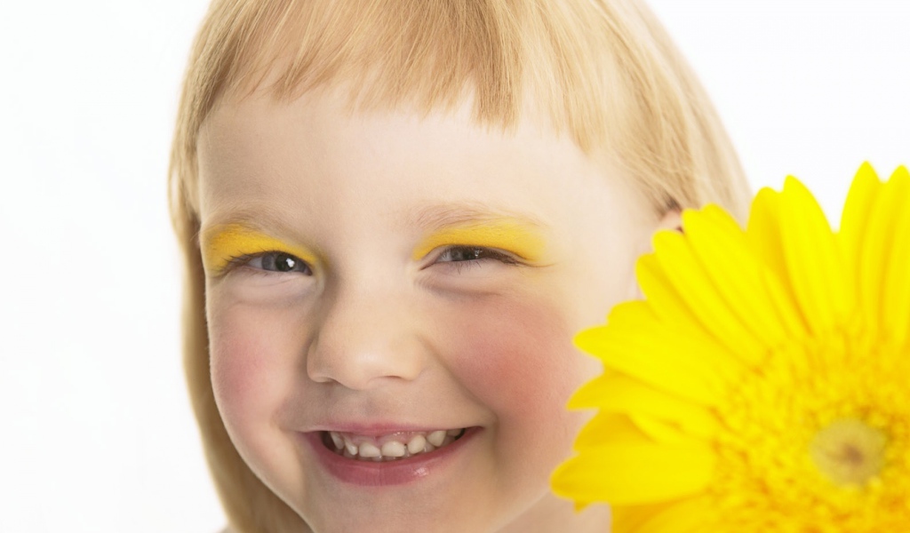 Улыбающаяся девочка с желтым цветком герберы