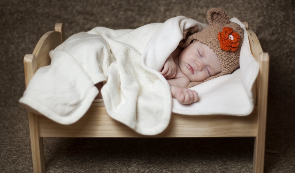 Грудной ребенок спит в маленькой кроватке
