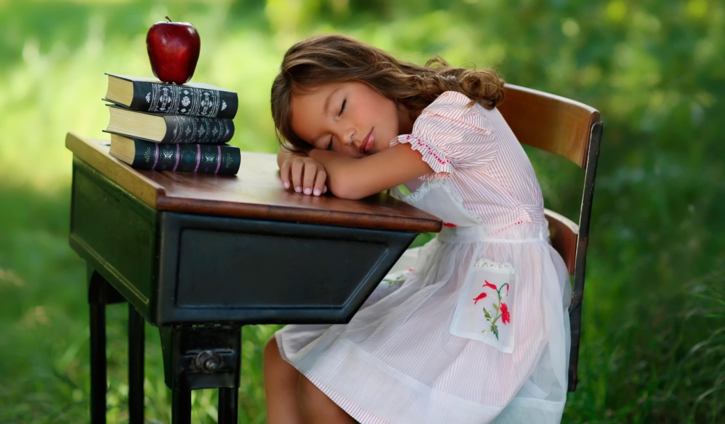 Уставшая маленькая ученица уснула за партой