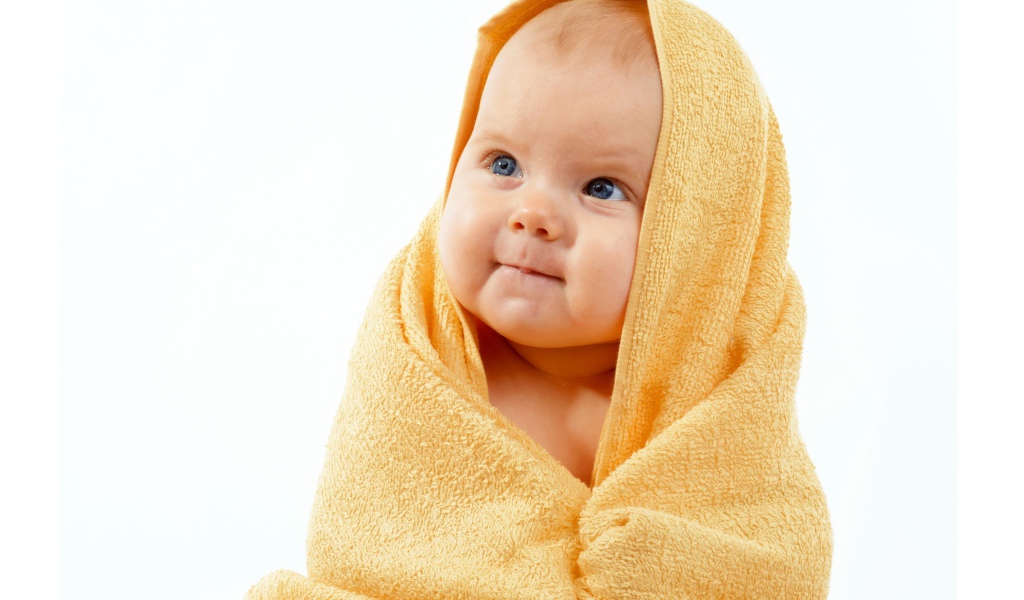 Грудной ребенок в желтом полотенце на белом фоне