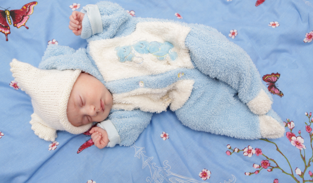 Грудной спящий ребенок в голубом костюме