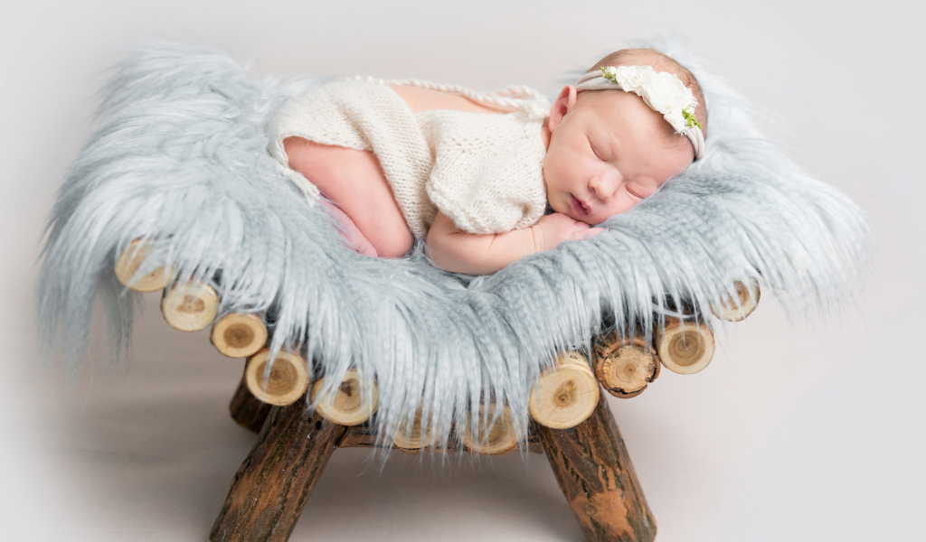 Грудной спящий ребенок лежит на деревянной кроватке