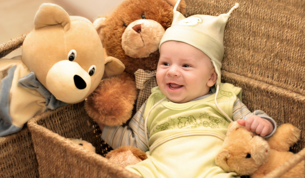 Грудной улыбающийся ребенок в корзине с игрушками