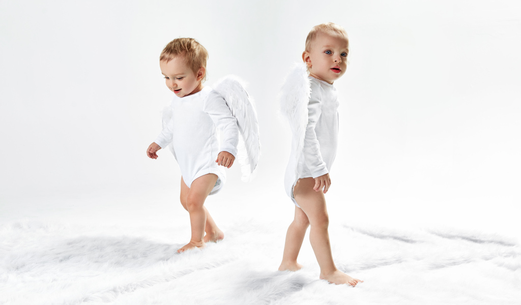 Два маленьких мальчика в костюмах ангела на белом фоне