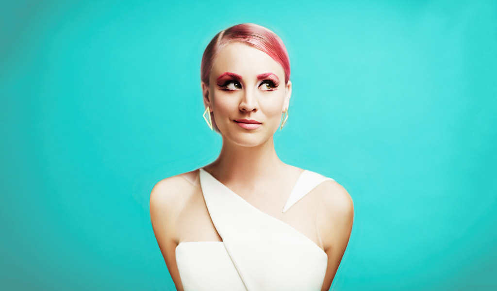 Актриса Кейли Куоко с ярким макияжем на голубом фоне