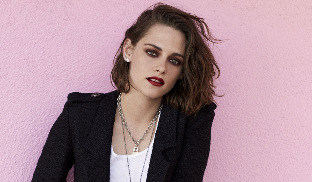 Актриса Кристен Стюарт в черном пиджаке на розовом фоне