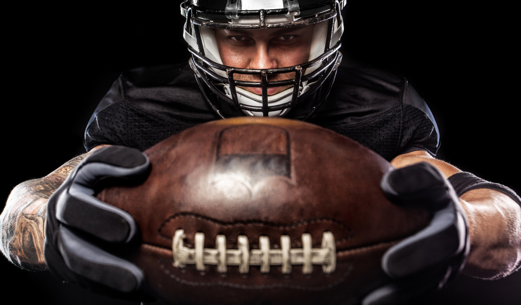 Американский футболист с мячом на черном фоне