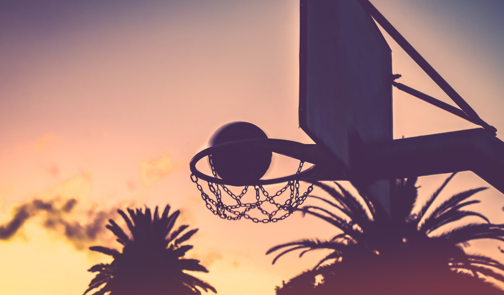 Баскетбольное кольцо с мячом на закате