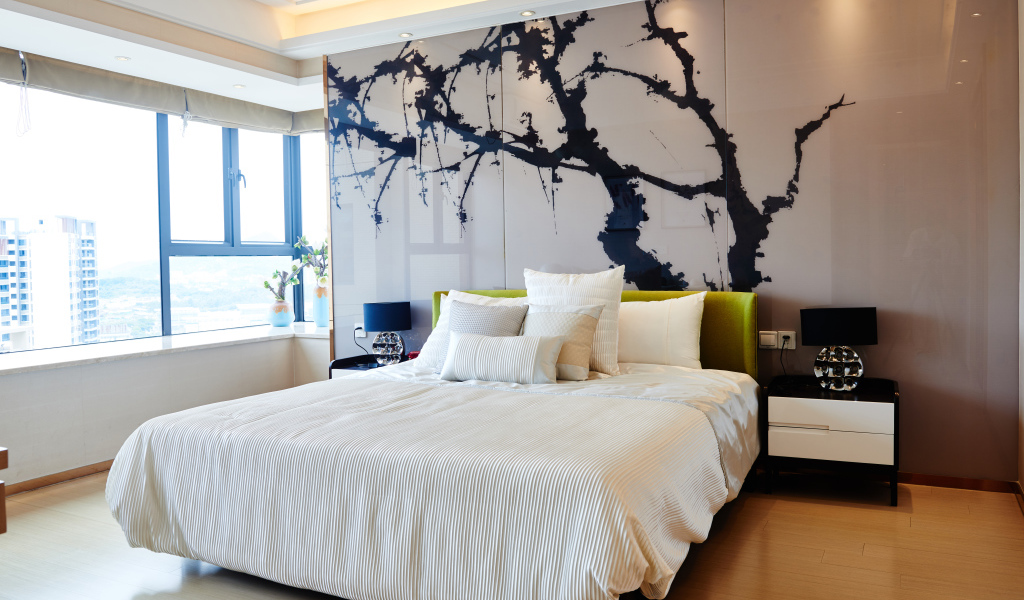 Красивая светлая спальня с большой кроватью и рисунком на стене 