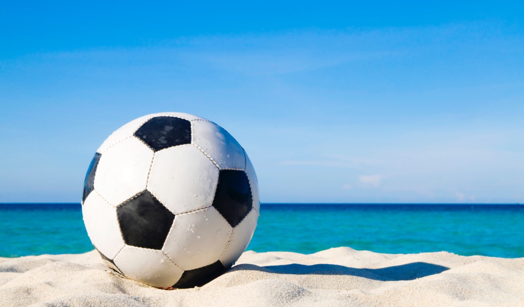 Футбольный мяч на белом песке на фоне голубого неба