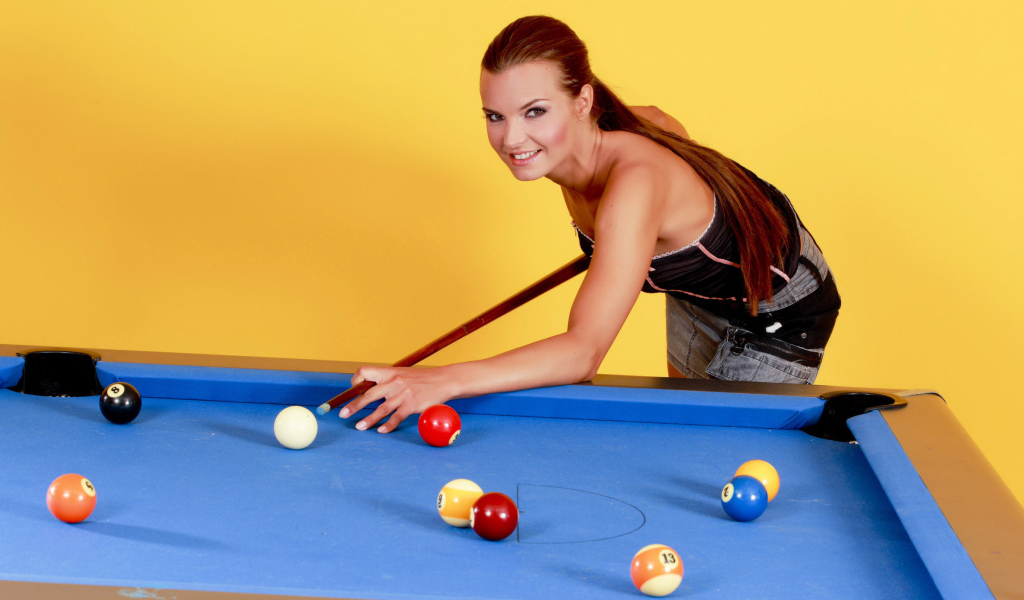 Молодая девушка играет в бильярд