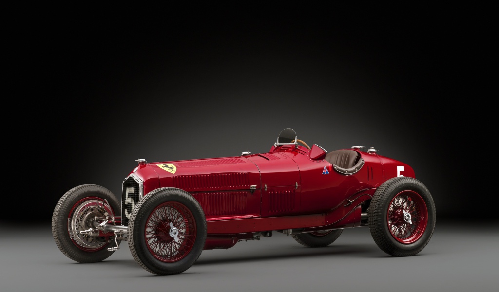 Красный ретро автомобиль Alfa Romeo на сером фоне