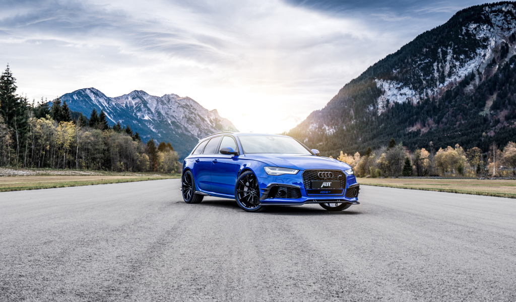 Синий автомобиль Audi RS 6 на фоне гор на дороге