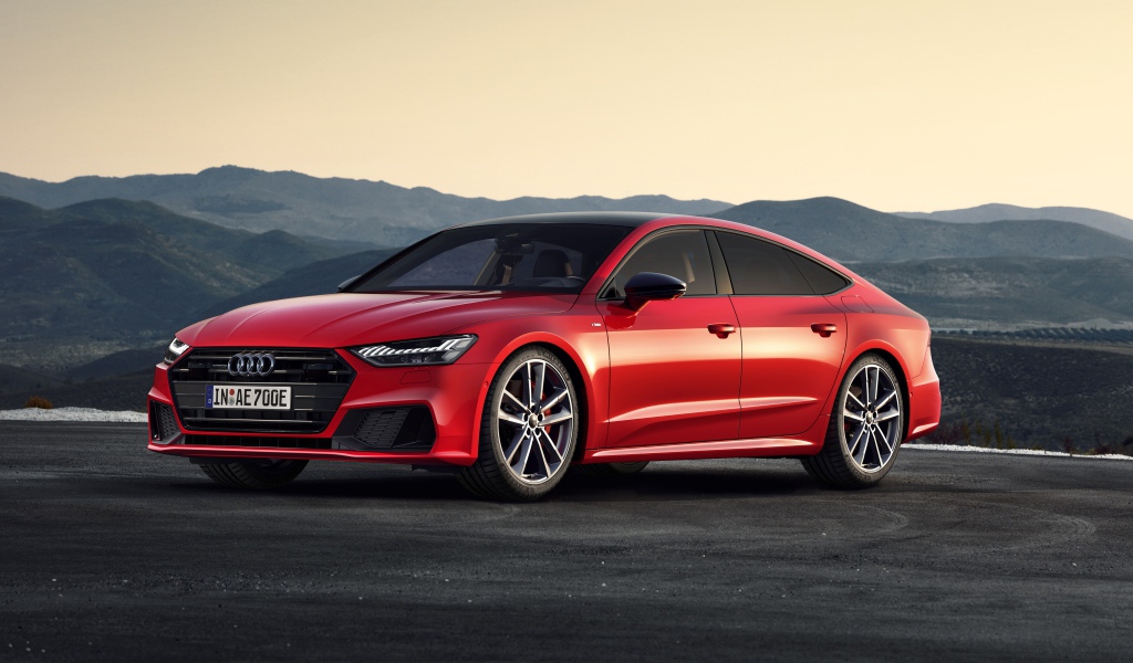 Красный автомобиль Audi A7 Sportback 55 TFSI E Quattro S Line 2019 года в горах