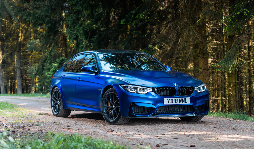 Синий автомобиль BMW M3 на фоне деревьев