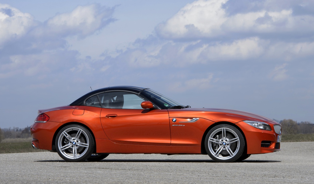 Оранжевый автомобиль BMW Z4 на фоне красивого неба
