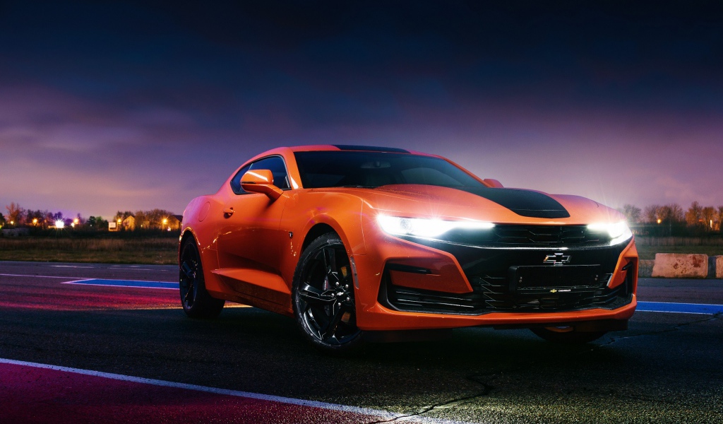 Оранжевый автомобиль Chevrolet Camaro, 2019 года с включенными фарами