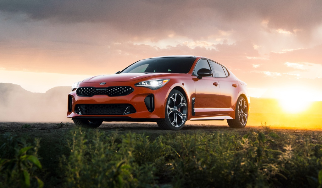 Оранжевый автомобиль  Kia Stinger GTS, 2020 года на закате