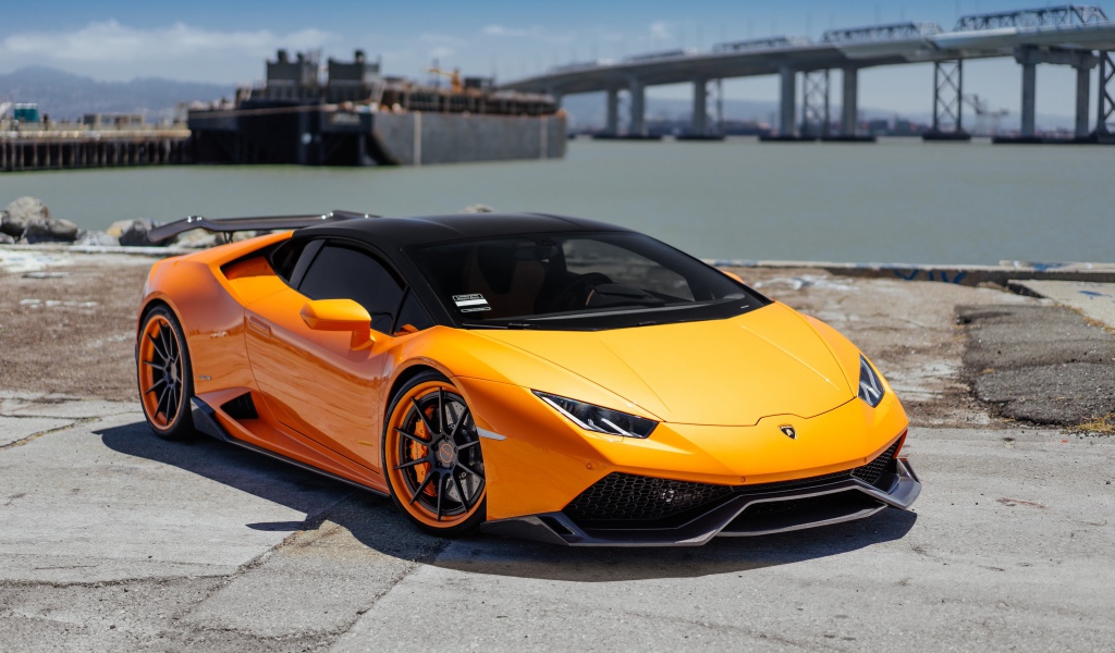 Оранжевый быстрый Lamborghini Huracan в порту у воды