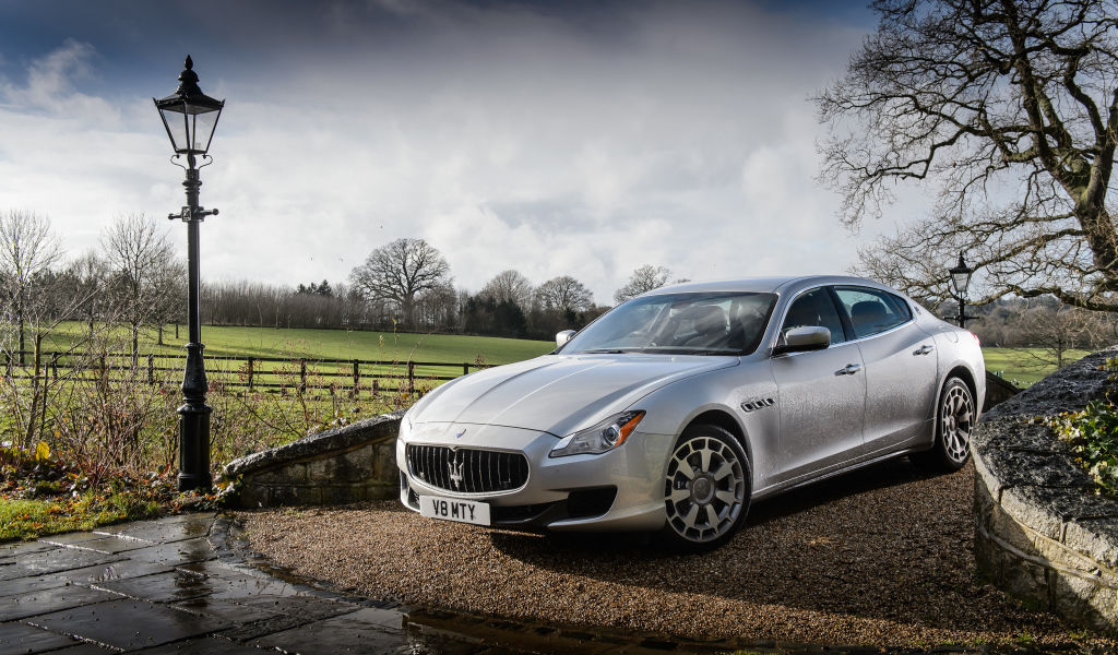 Серебристый стильный дорогой автомобиль Maserati Quattroporte на дороге после дождя