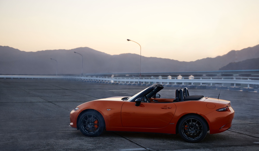 Оранжевый автомобиль кабриолет Mazda MX-5 на фоне неба