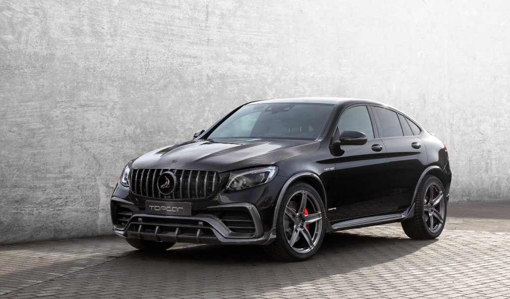 Черный автомобиль Mercedes-AMG GLC 63 на фоне серой стены 