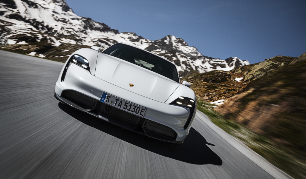 Белый автомобиль Porsche Taycan Turbo S 2019 года на фоне заснеженных гор