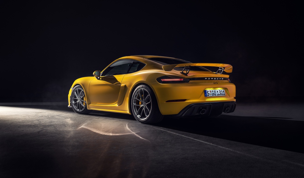 Желтый автомобиль Porsche 718 Cayman GT4, 2019 года вид сзади