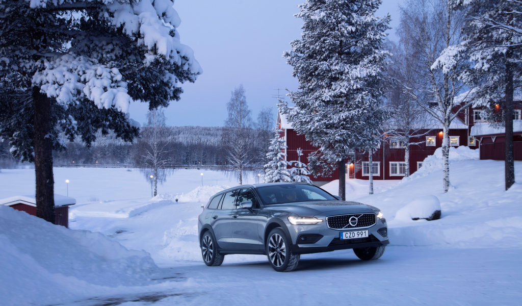 Автомобиль Volvo V60 на фоне заснеженных деревьев 