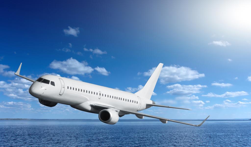 Большой белый пассажирский самолет летит над морем