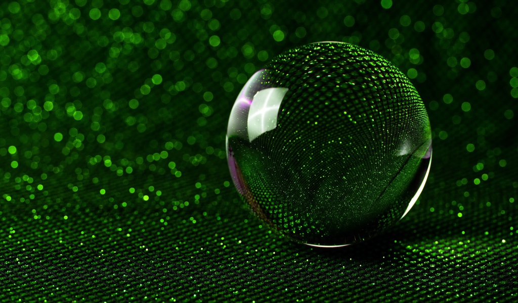 Большой стеклянный шар на зеленом блестящем фоне