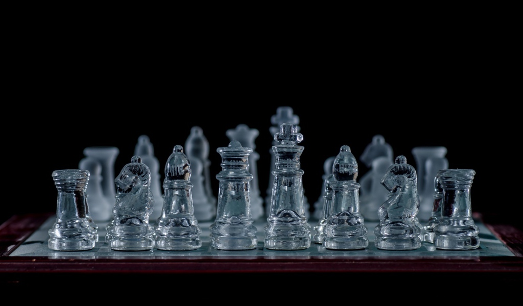 Стеклянные шахматы на доске на черном фоне