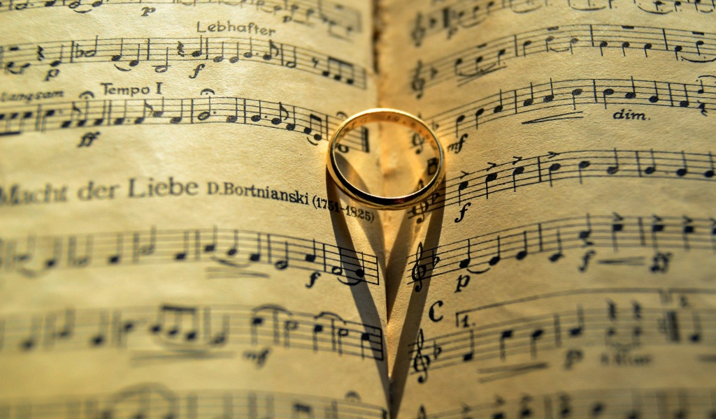 Золотое обручальное кольцо лежит на нотной тетради