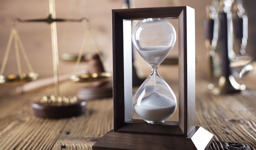 Песочные часы на столе с весами крупным планом