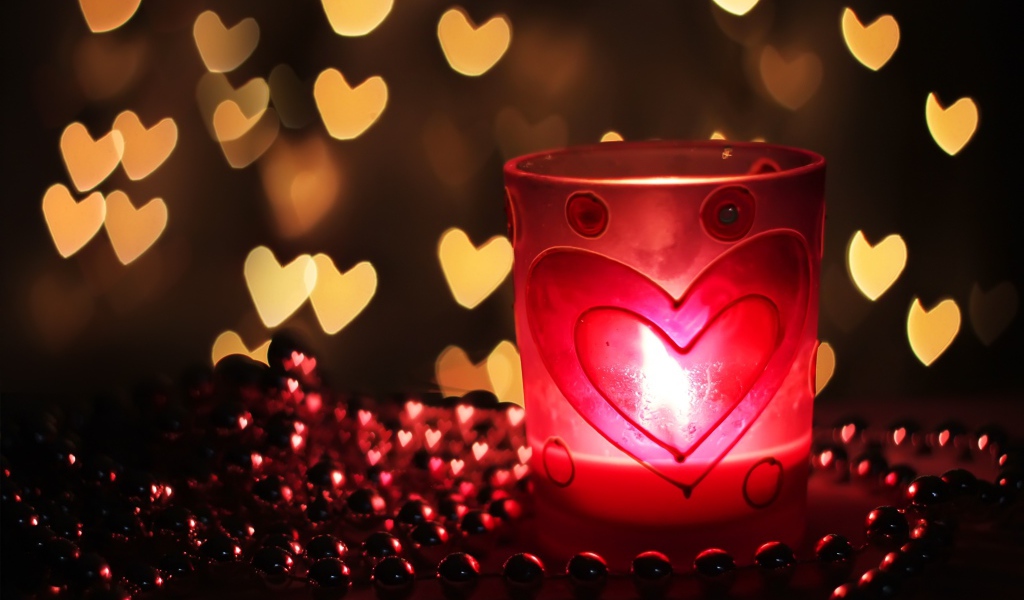 Зажженная свеча на столе с бусами 