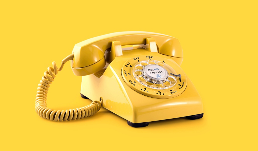 Старый желтый телефон на желтом фоне
