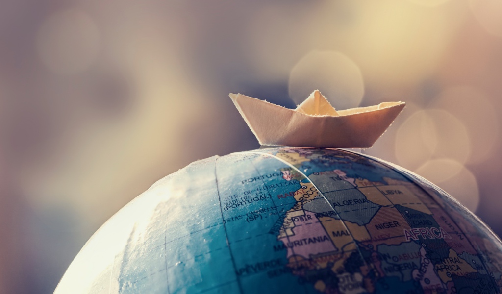 Бумажный кораблик лежит на глобусе